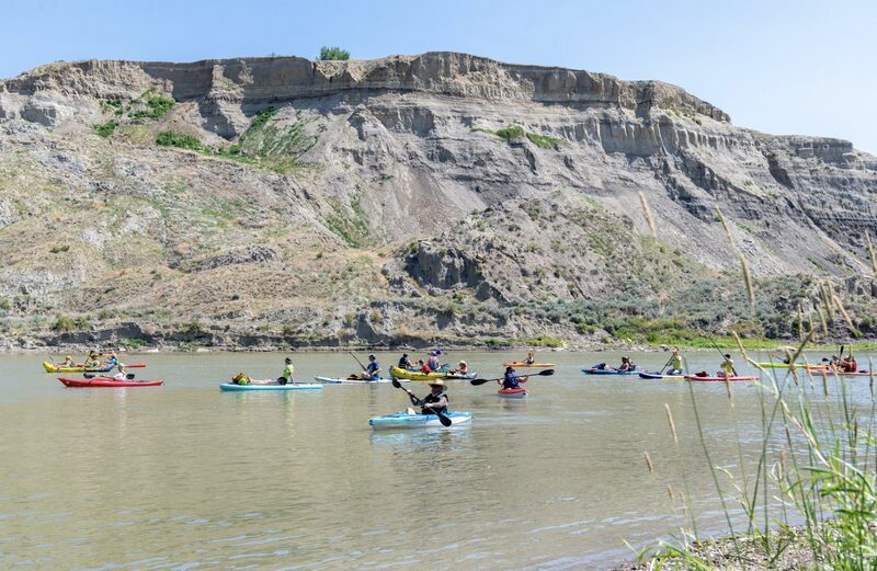 group of people paddling the river by the redcliffs